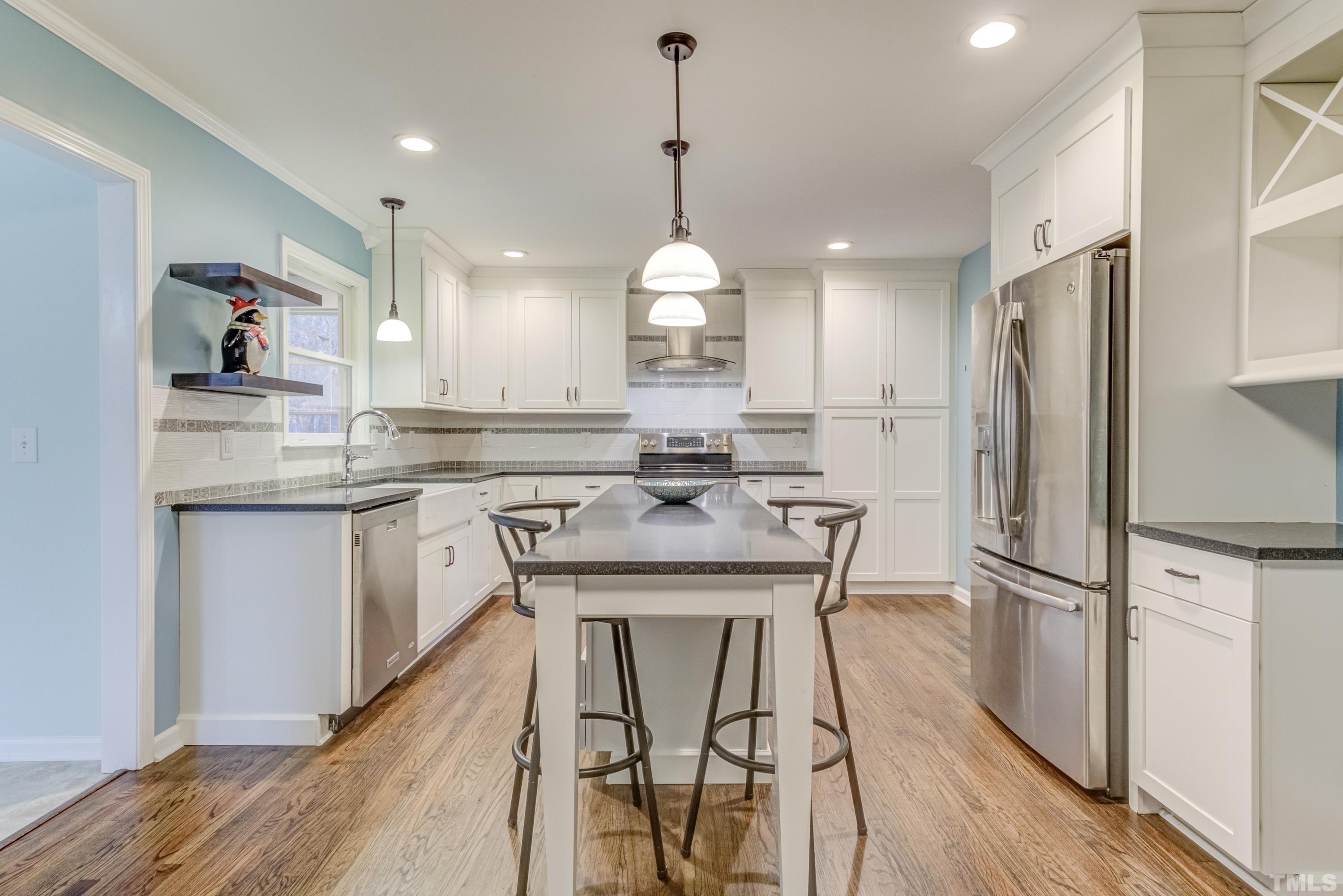 605 Jordan Ridge Lane Raleigh, NC 27603 - Photo 8 of 36 a kitchen with kitchen island granite countertop wooden floors white cabinets and stainless steel appliances
