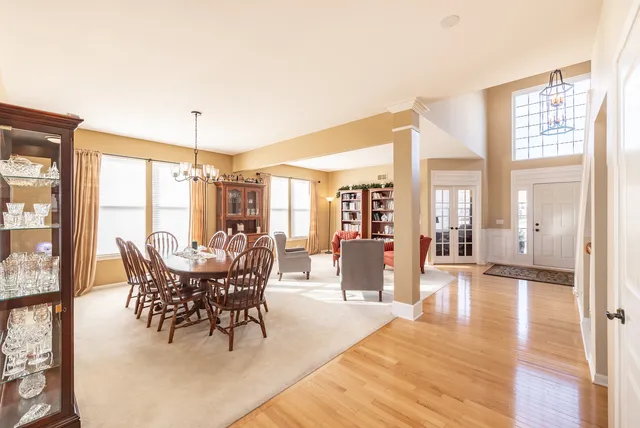 a dining room with wooden floor a chandelier a glass table and chairs