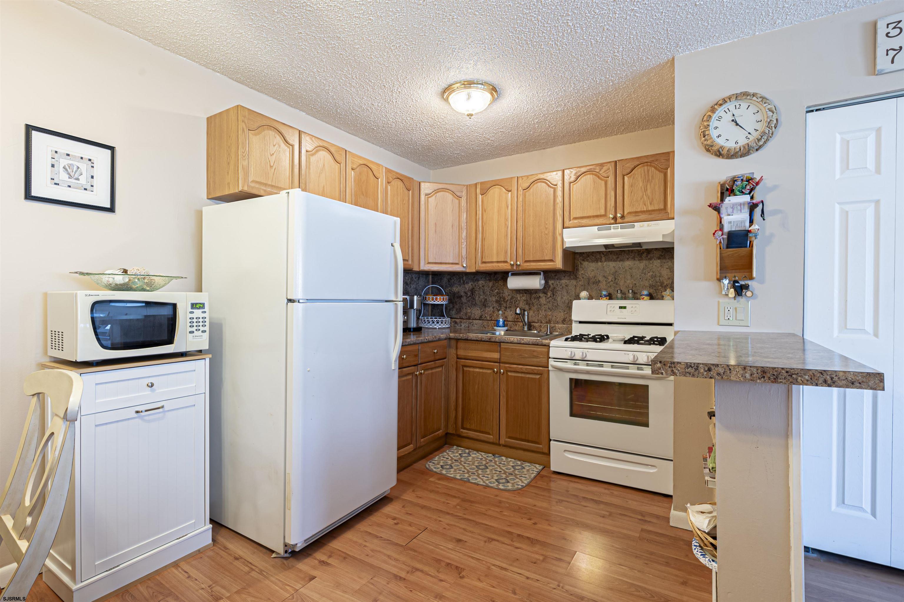 4901 Harbor Beach Boulevard, Unit Q3 Brigantine, NJ 08203 - Photo 8 of 19 a kitchen with a refrigerator a stove top oven a clock and a window