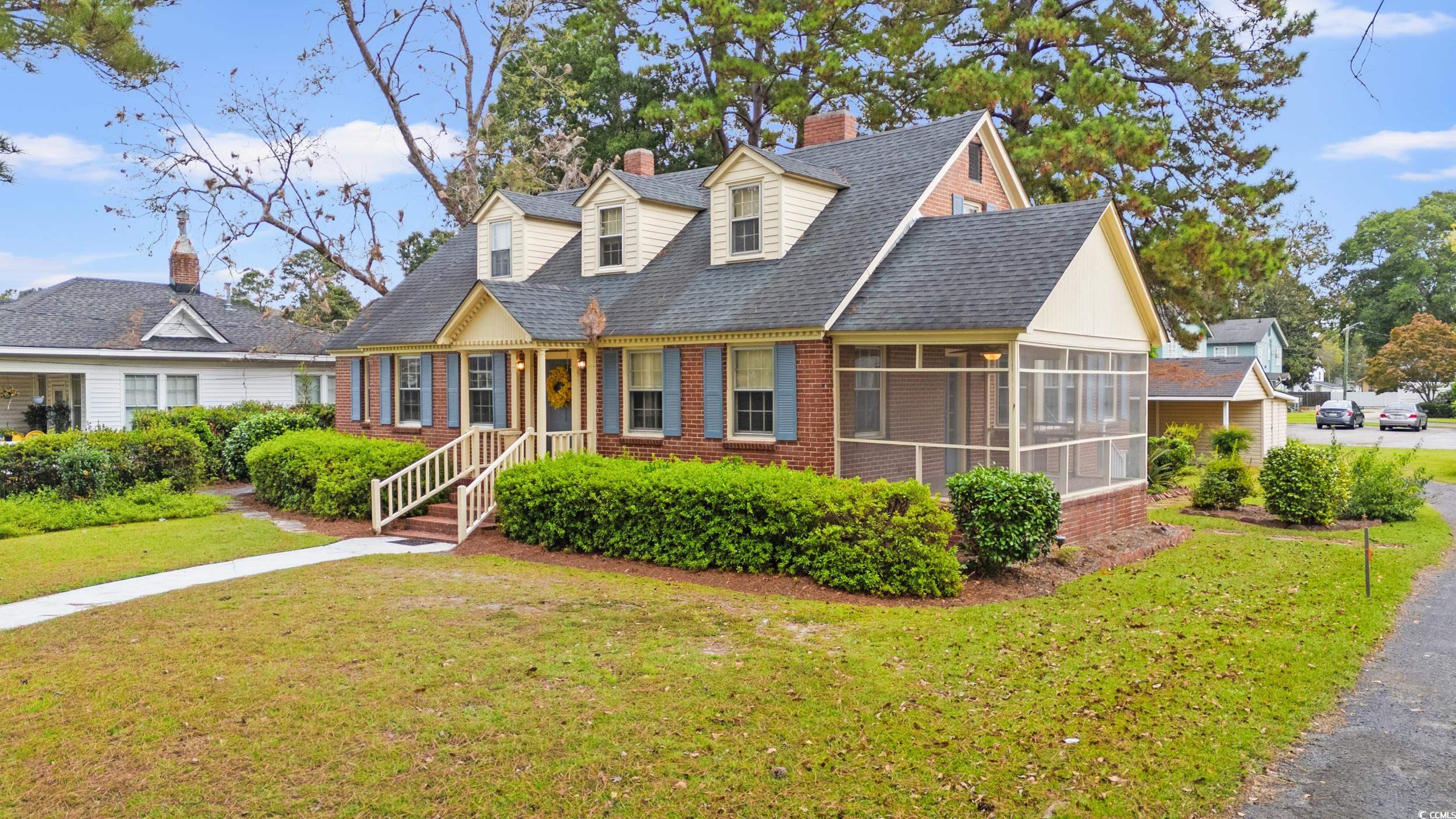 310 North Main Street Mullins, SC 29574 - Photo 5 of 35 Cape cod house with a front yard, a chimney, a shingled roof, and a sunroom
