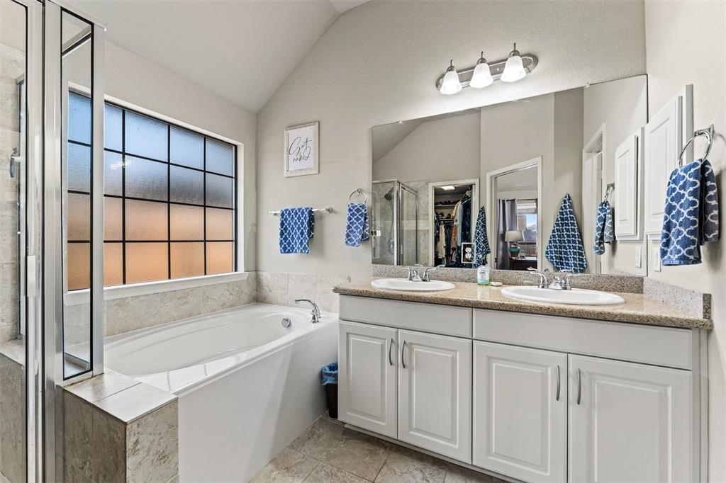 10313 Condor Loop Waco, TX 76708 - Photo 24 of 33 Dual vanity with undermount sinks, spacious bathtub, separate shower enclosure with glass panels, and a large privacy window