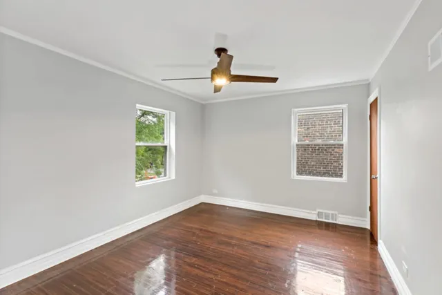 a view of empty room with wooden floor and fan