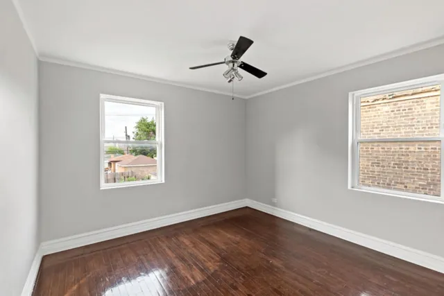 a view of empty room with wooden floor and fan