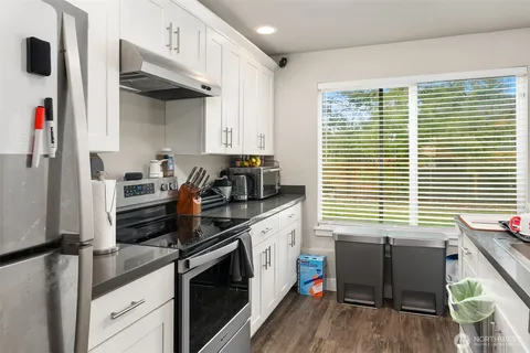 a kitchen with stainless steel appliances a white cabinets and a window