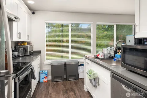 a kitchen with stainless steel appliances a sink a stove a refrigerator wooden floor and a large window