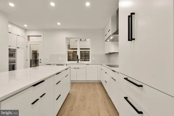 a large white kitchen with granite countertop a sink and dishwasher with a large window