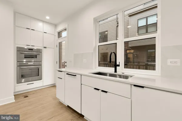 a kitchen with stainless steel appliances cabinets a sink and a large window