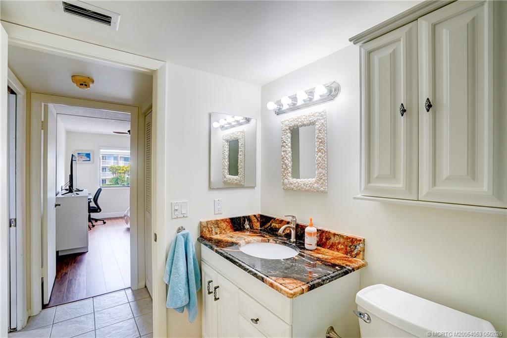 10 Northeast Plantation Road, Unit 101 Jensen Beach, FL 34957 - Photo 45 of 53 a bathroom with a granite countertop sink and a mirror