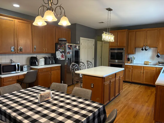 a kitchen with stainless steel appliances kitchen island granite countertop a table chairs and a refrigerator