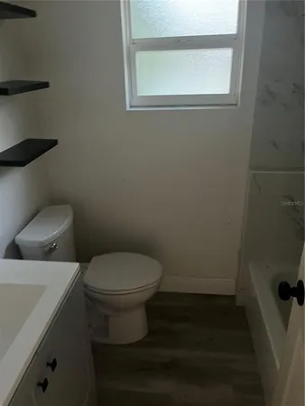 a white toilet sitting in a bathroom next to a window