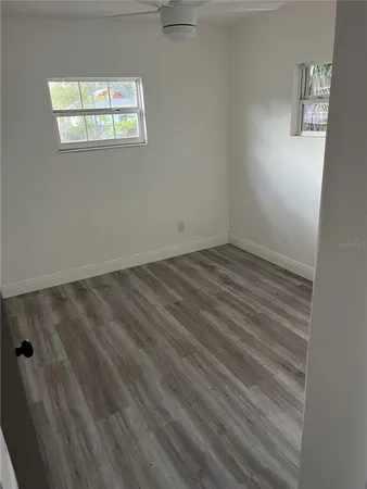 a view of an empty room with wooden floor and a window