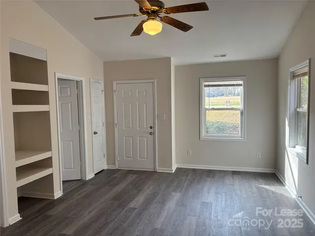 a view of an empty room with a window and wooden floor