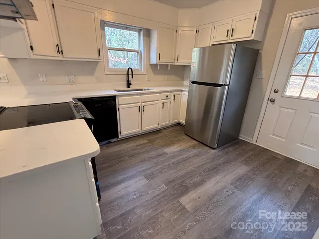 a kitchen with a sink a refrigerator a window and cabinets