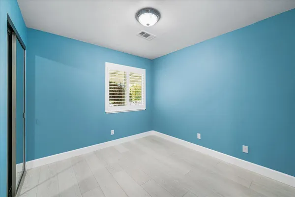 an empty room with a window and ceiling fan