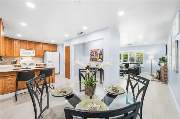 a kitchen with stainless steel appliances granite countertop a dining table chairs and view of living room