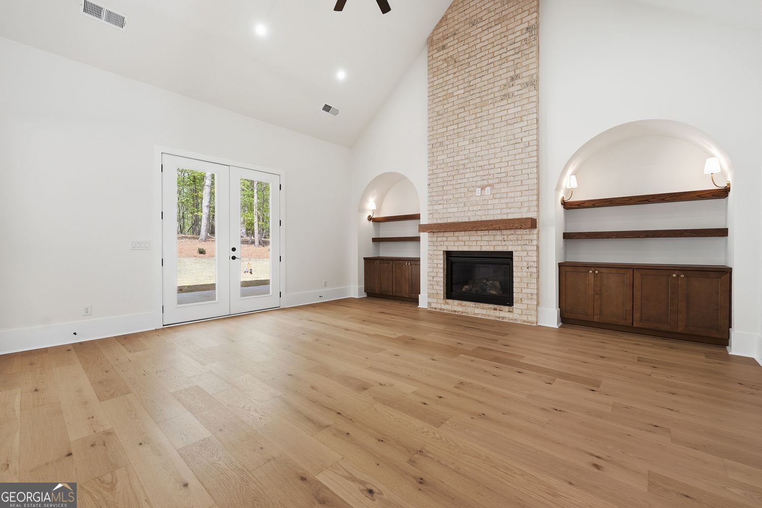 6625 Windvane Point Clermont, GA 30527 - Photo 16 of 45 an empty room with wooden floor fireplace and windows