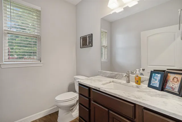 a bathroom with a granite countertop toilet sink and mirror