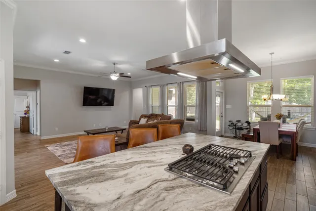 a large living room with stainless steel appliances granite countertop a stove top oven a dining table and chairs with wooden floor