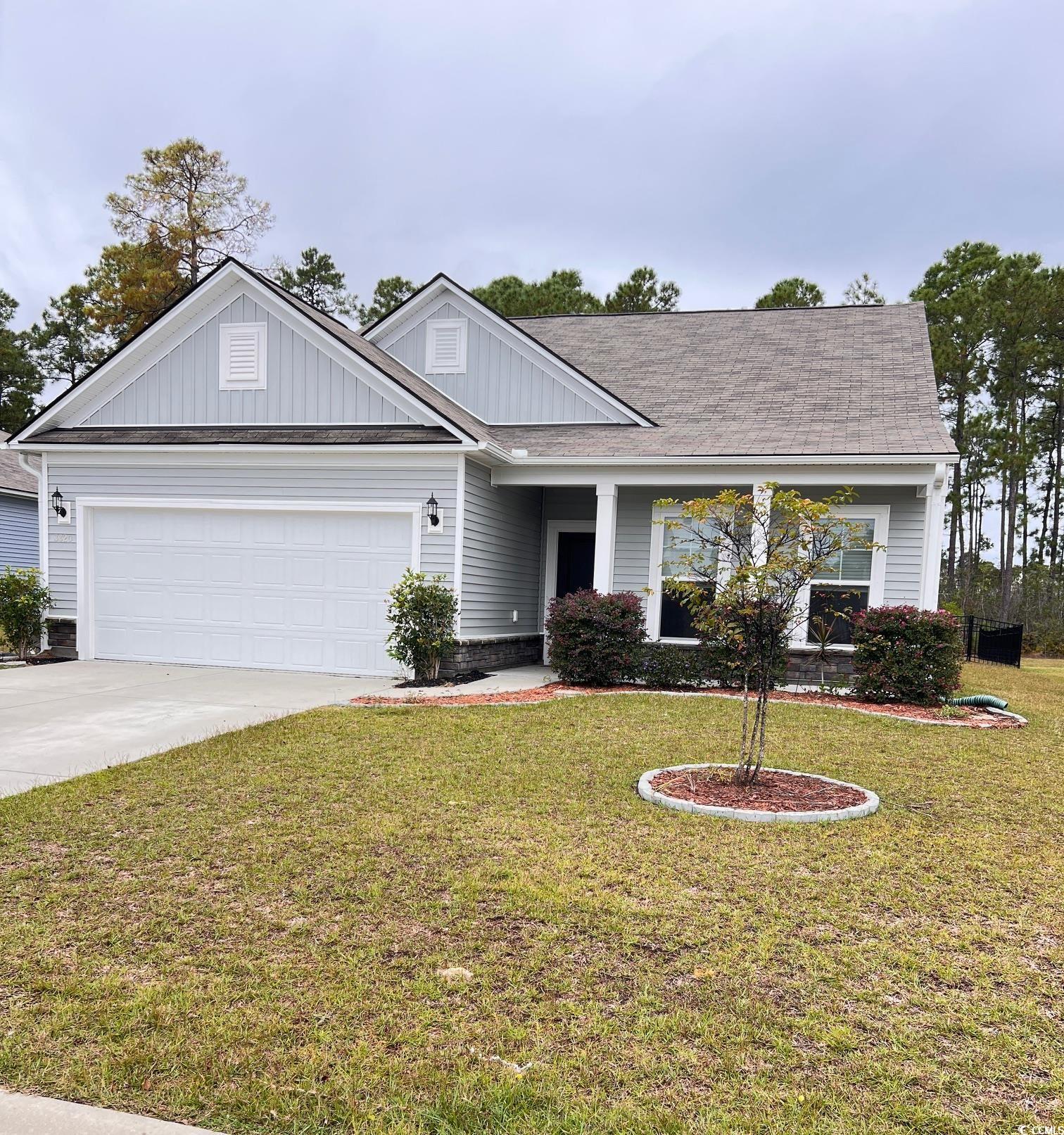 View of front of home featuring a front yard, concrete driveway, and an attached garage