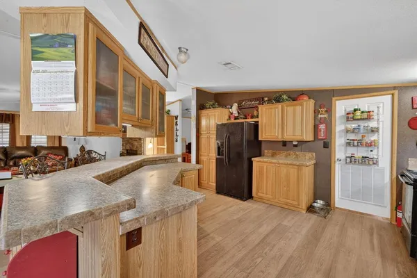 a kitchen with a refrigerator a stove a sink dishwasher and wooden cabinets with wooden floor