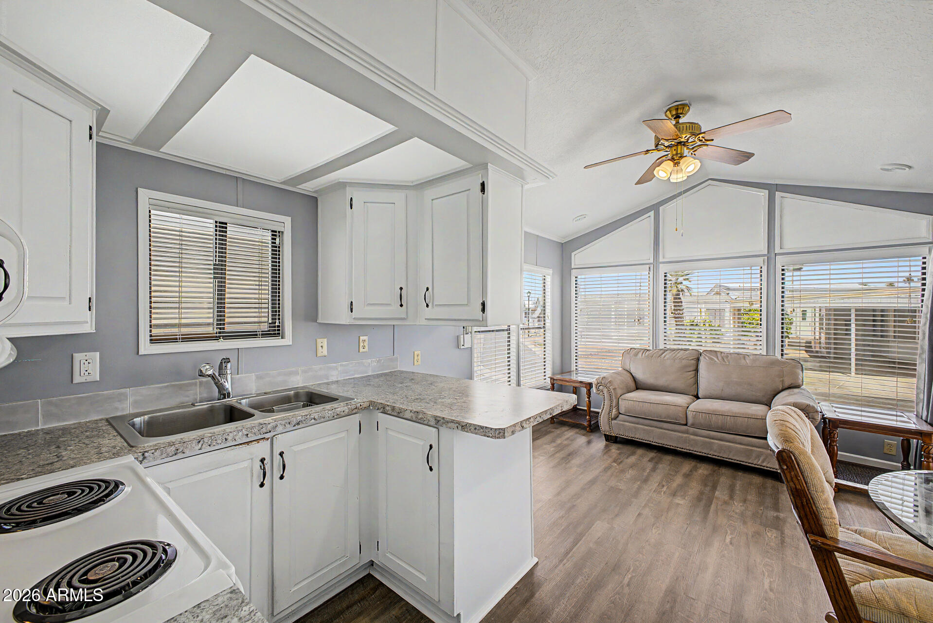 7750 East Broadway Road, Unit 560 Mesa, AZ 85208 - Photo 5 of 18 a kitchen with a sink dishwasher a stove and white cabinets with wooden floor