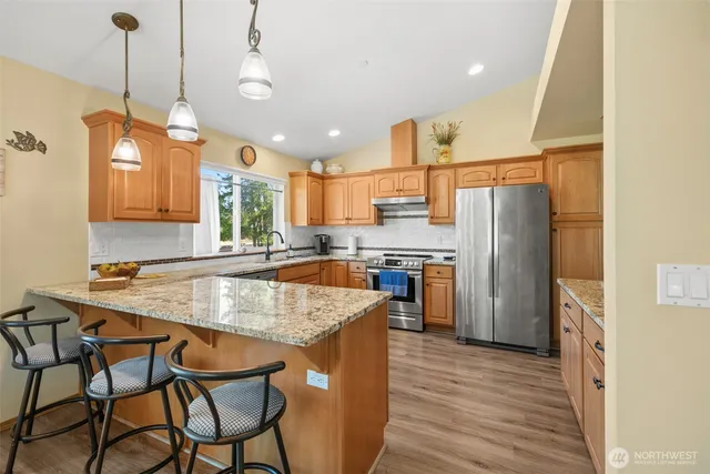 a kitchen with stainless steel appliances granite countertop a sink refrigerator and cabinets