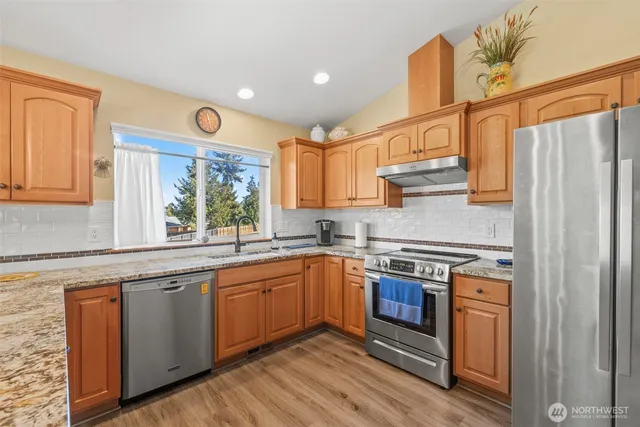 a kitchen with stainless steel appliances granite countertop a refrigerator stove and sink