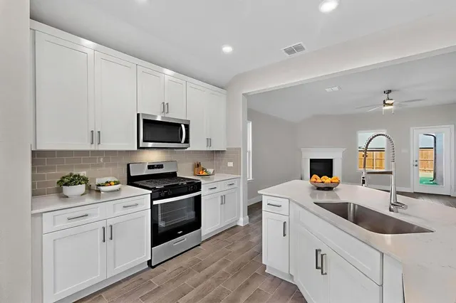 a kitchen with granite countertop white cabinets white stainless steel appliances and sink
