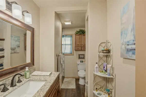 a bathroom with a sink a toilet a mirror a vanity a window and shower