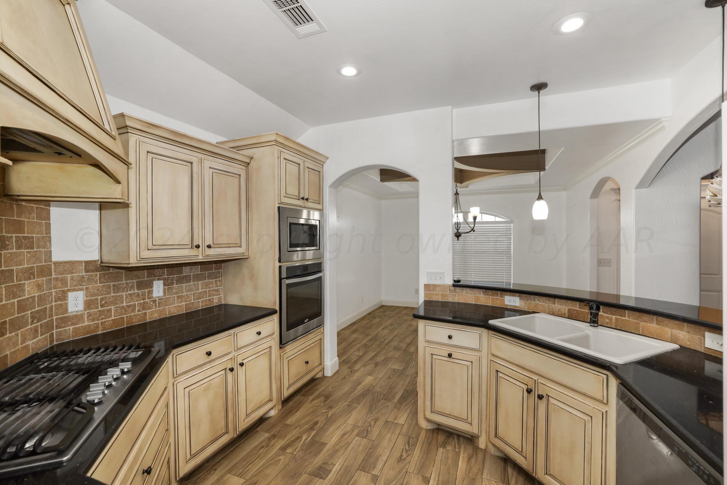 7303 Rochester Drive Amarillo, TX 79118 - Photo 9 of 38 a kitchen with granite countertop a sink cabinets and stainless steel appliances