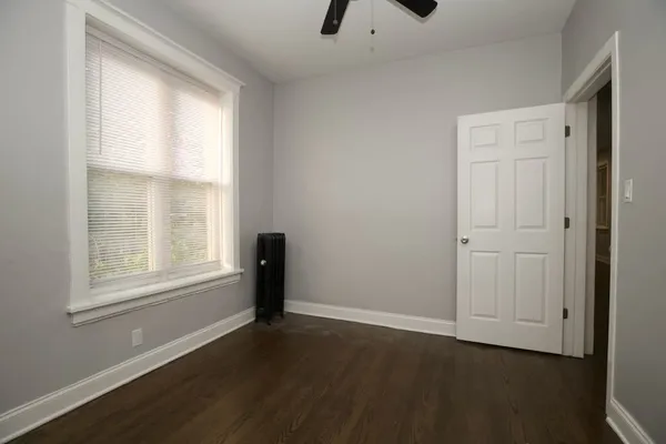 an empty room with wooden floor cabinet and windows