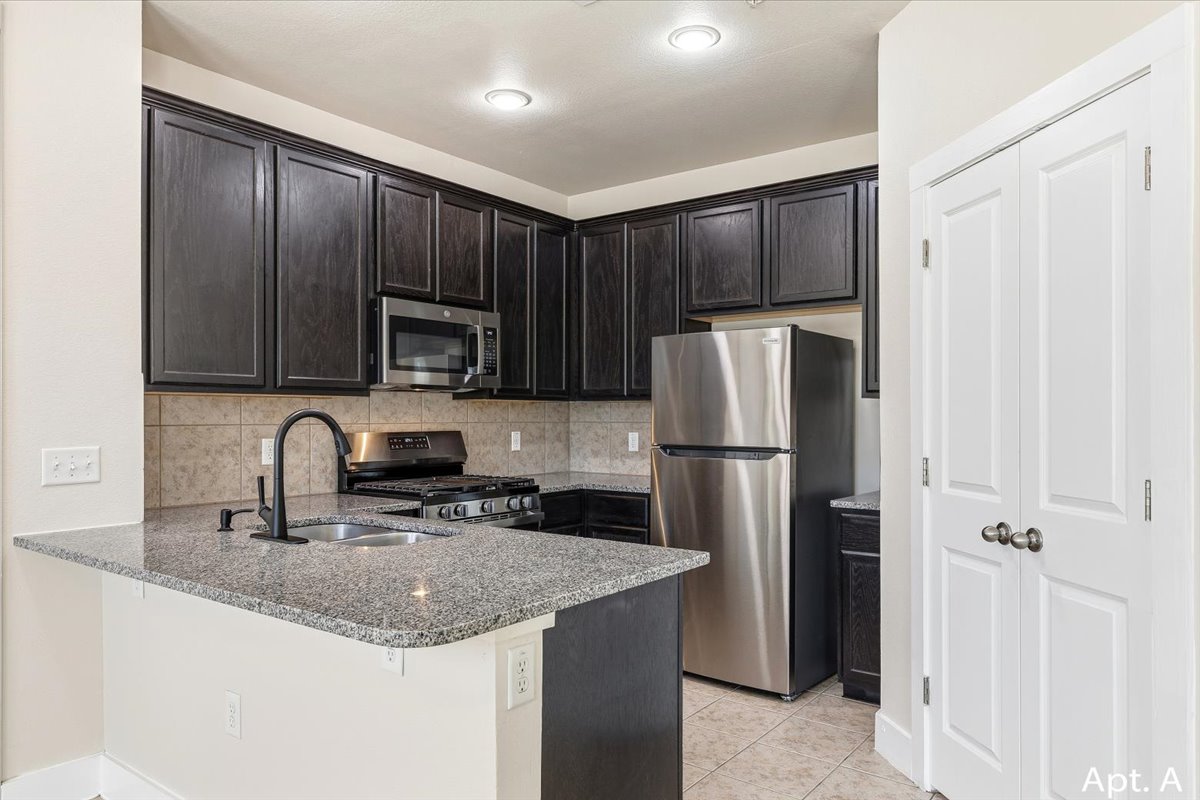 2225 Katy Lane, Unit A Georgetown, TX 78626 - Photo 8 of 22 Kitchen featuring stainless steel appliances, a peninsula, dark stone countertops, decorative backsplash, and a breakfast bar area