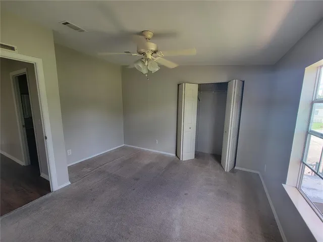an empty room with windows and fan