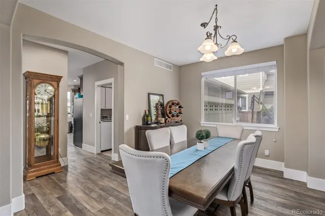 a dining room with wooden floor a chandelier a wooden table and chairs
