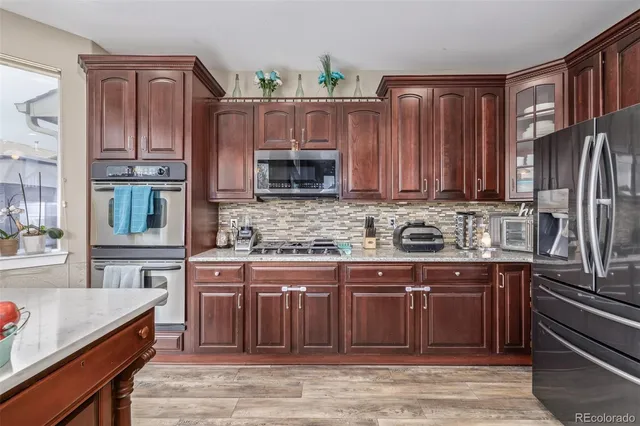 a kitchen with stainless steel appliances granite countertop a stove top oven a sink and dishwasher a oven with wooden cabinets