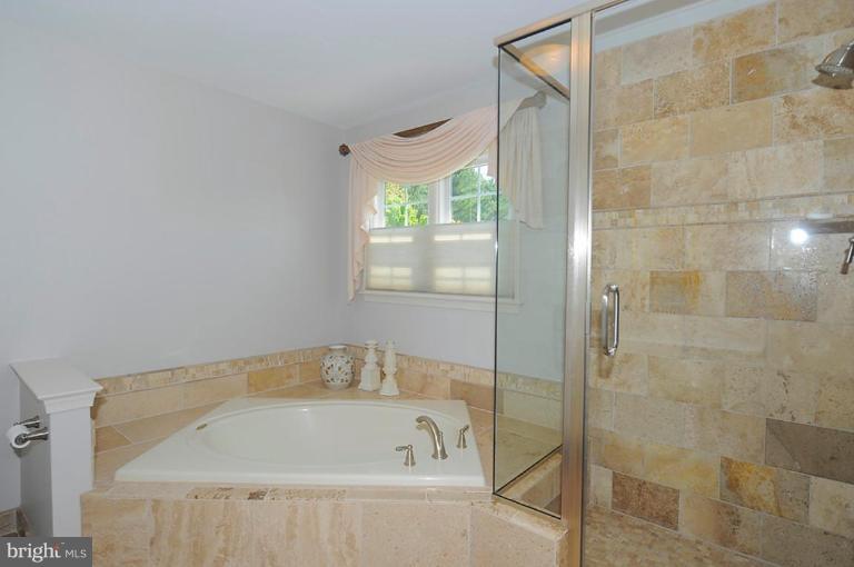 6583 Forsythia Street Springfield, VA 22150 - Photo 14 of 28 a bathroom with a tub and shower