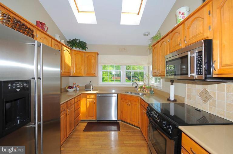6583 Forsythia Street Springfield, VA 22150 - Photo 7 of 28 a kitchen with stainless steel appliances granite countertop a sink a stove and a refrigerator