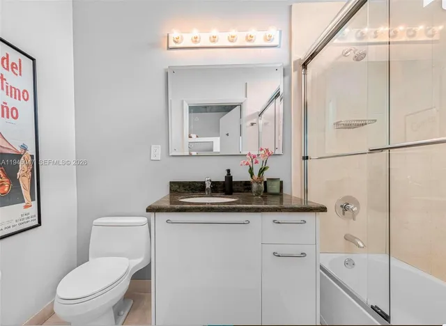a bathroom with a granite countertop sink toilet and mirror