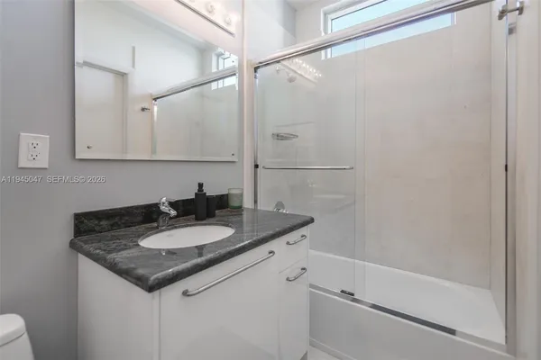 a bathroom with a granite countertop sink and a mirror