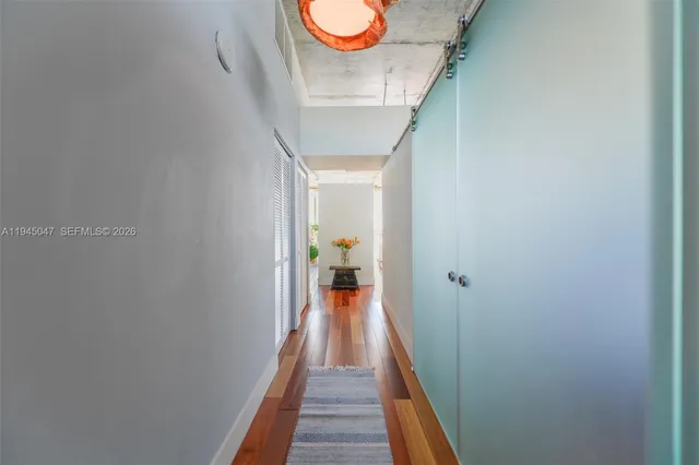 a view of a hallway with wooden floor and a bathroom