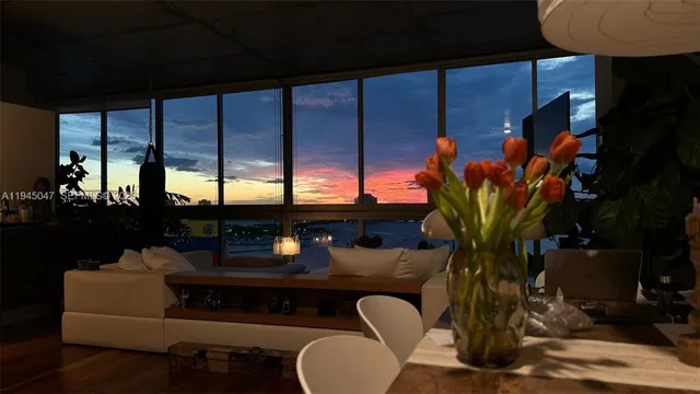 a living room with furniture a potted plant and a large window