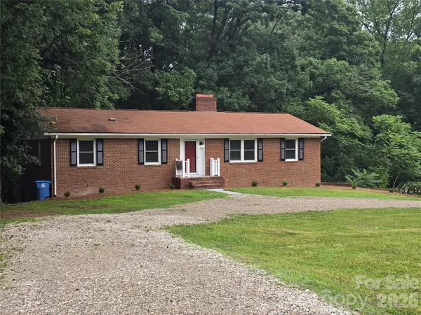 a view of a yard in front of a house with large trees