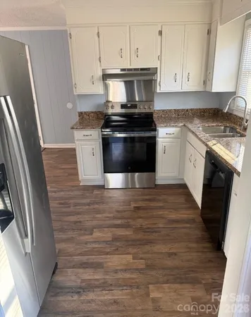 a kitchen with granite countertop a stove sink and refrigerator