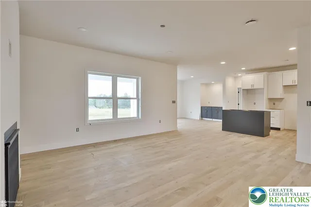 a view of an empty room with a window and a kitchen