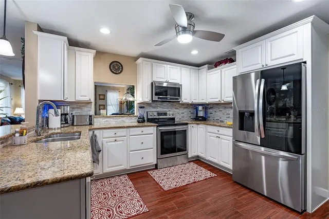 a kitchen with stainless steel appliances granite countertop a stove refrigerator sink and microwave