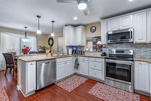 a large kitchen with stainless steel appliances granite countertop a stove and a wooden floors