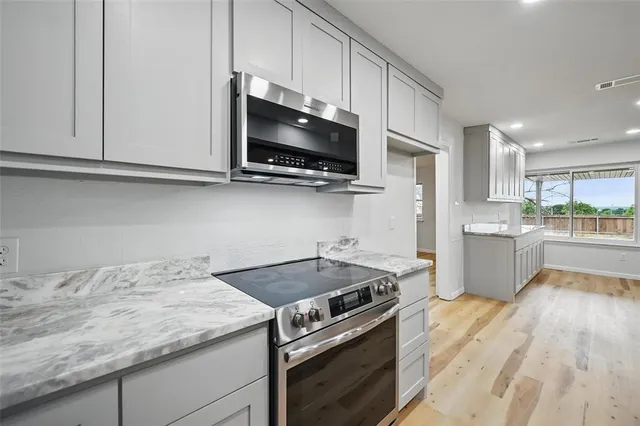 a kitchen with granite countertop cabinets stainless steel appliances and wooden floor
