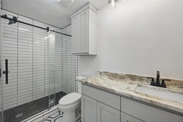 a bathroom with a granite countertop sink toilet and a mirror