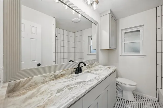 a bathroom with a granite countertop sink a toilet and a mirror