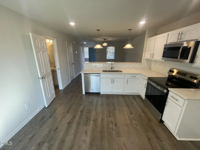 a large kitchen with a sink and dishwasher stove a refrigerator with wooden floor